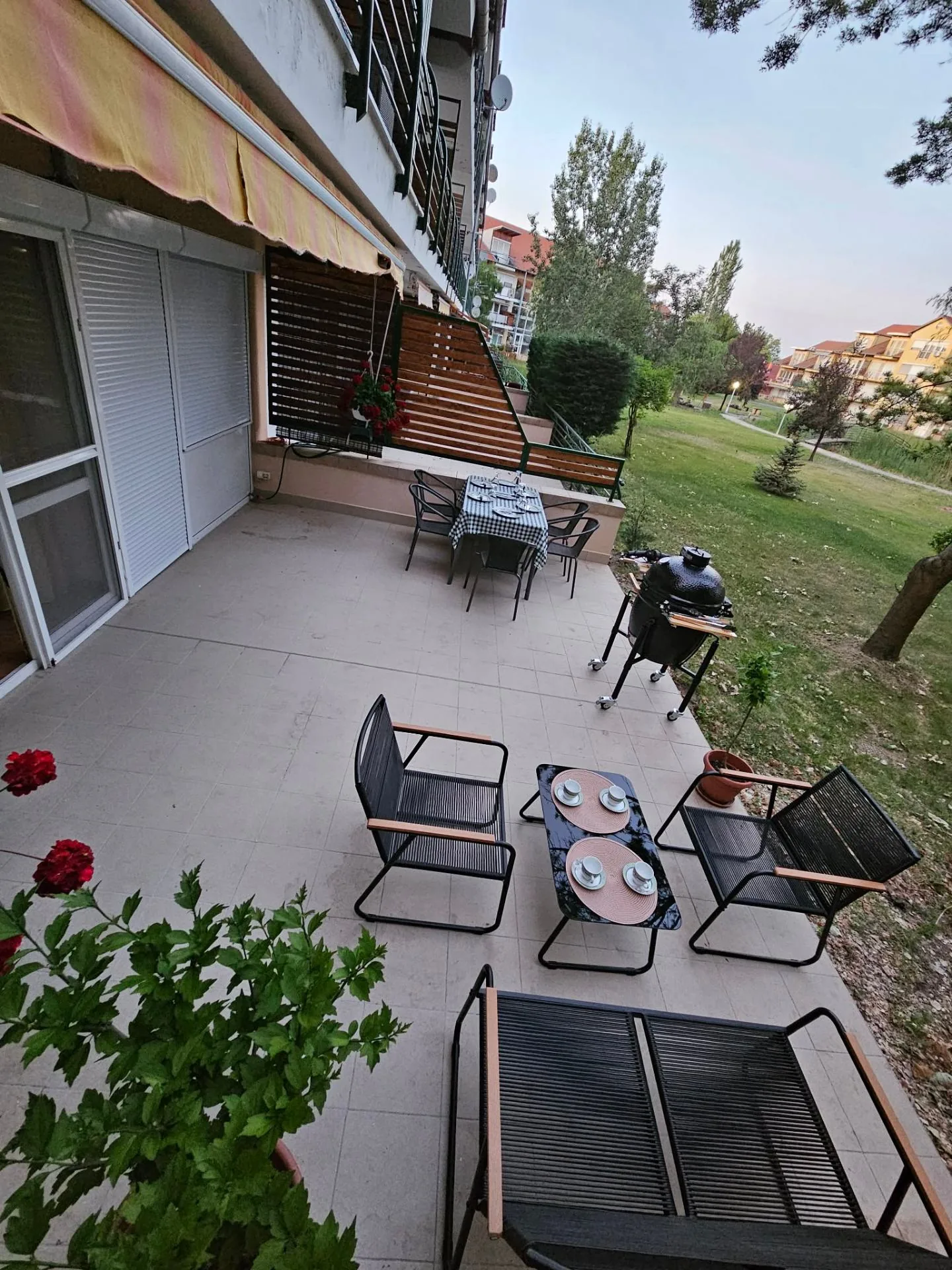 Tágas terasz kamado grillel, étkezőasztallal és zöld parkra néző kilátással