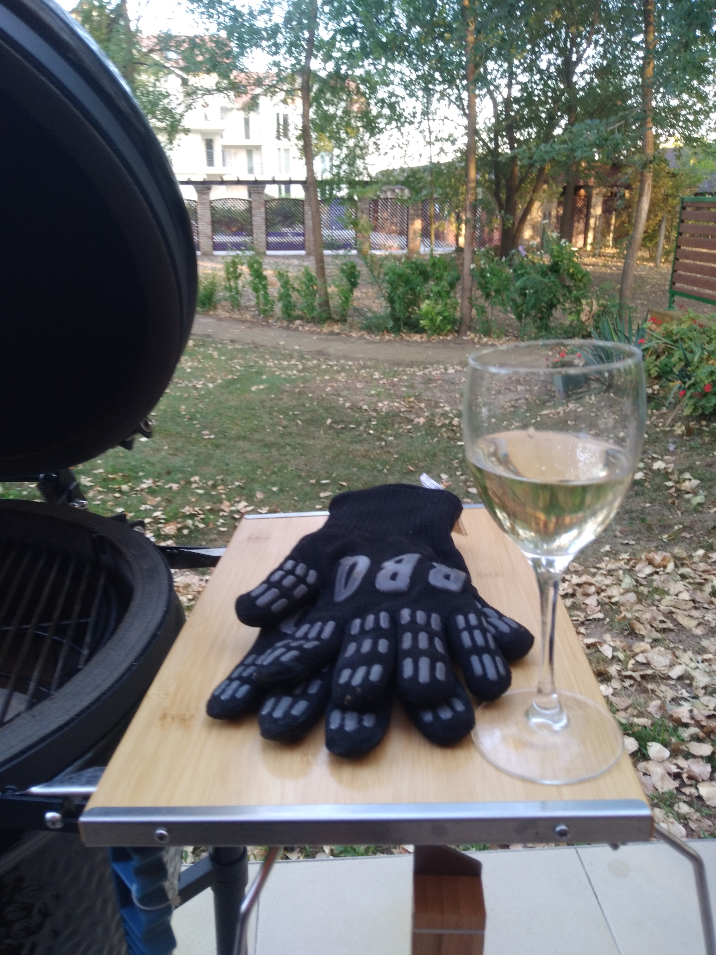Kamado grill BBQ kesztyűvel és egy pohár fehér borral a parkra néző cserkeszőlői teraszon