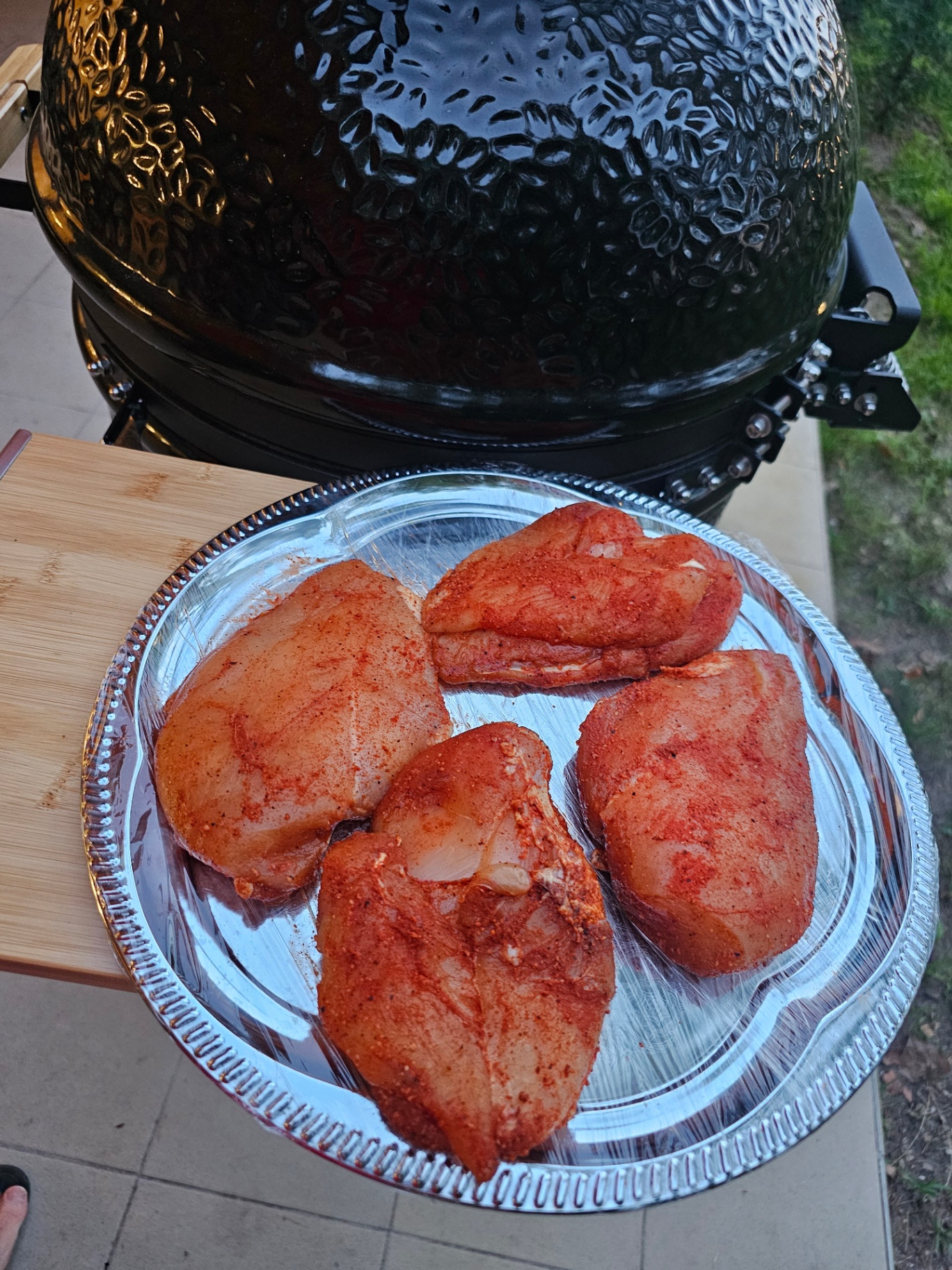 Pácolt nyers csirkemellek alutálcán a Monolith kamado mellett