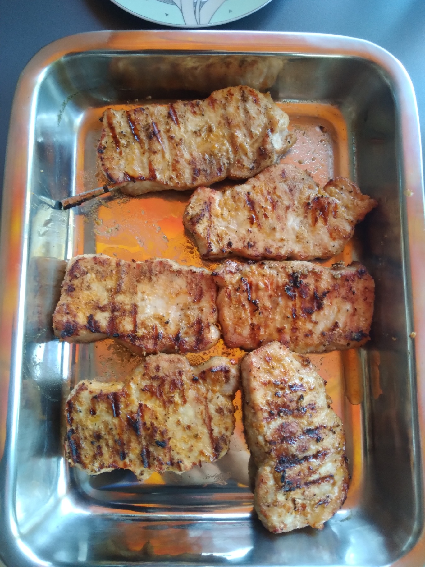 Grillezett tarjaszeletek inox tepsiben pihentetve a kamado grill mellett