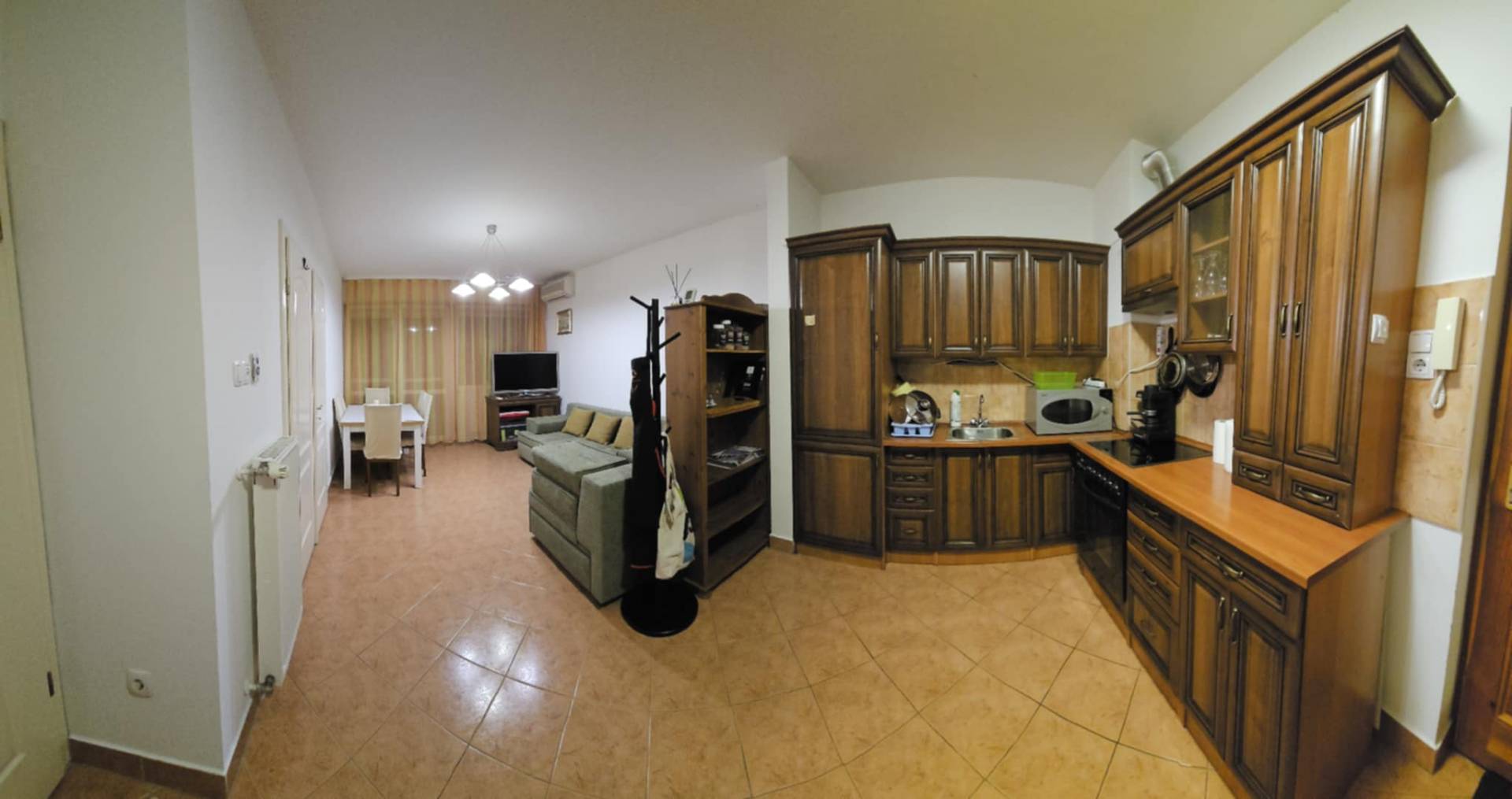 Panorámás nappali étkezővel, zöld kanapéval és fa konyhával