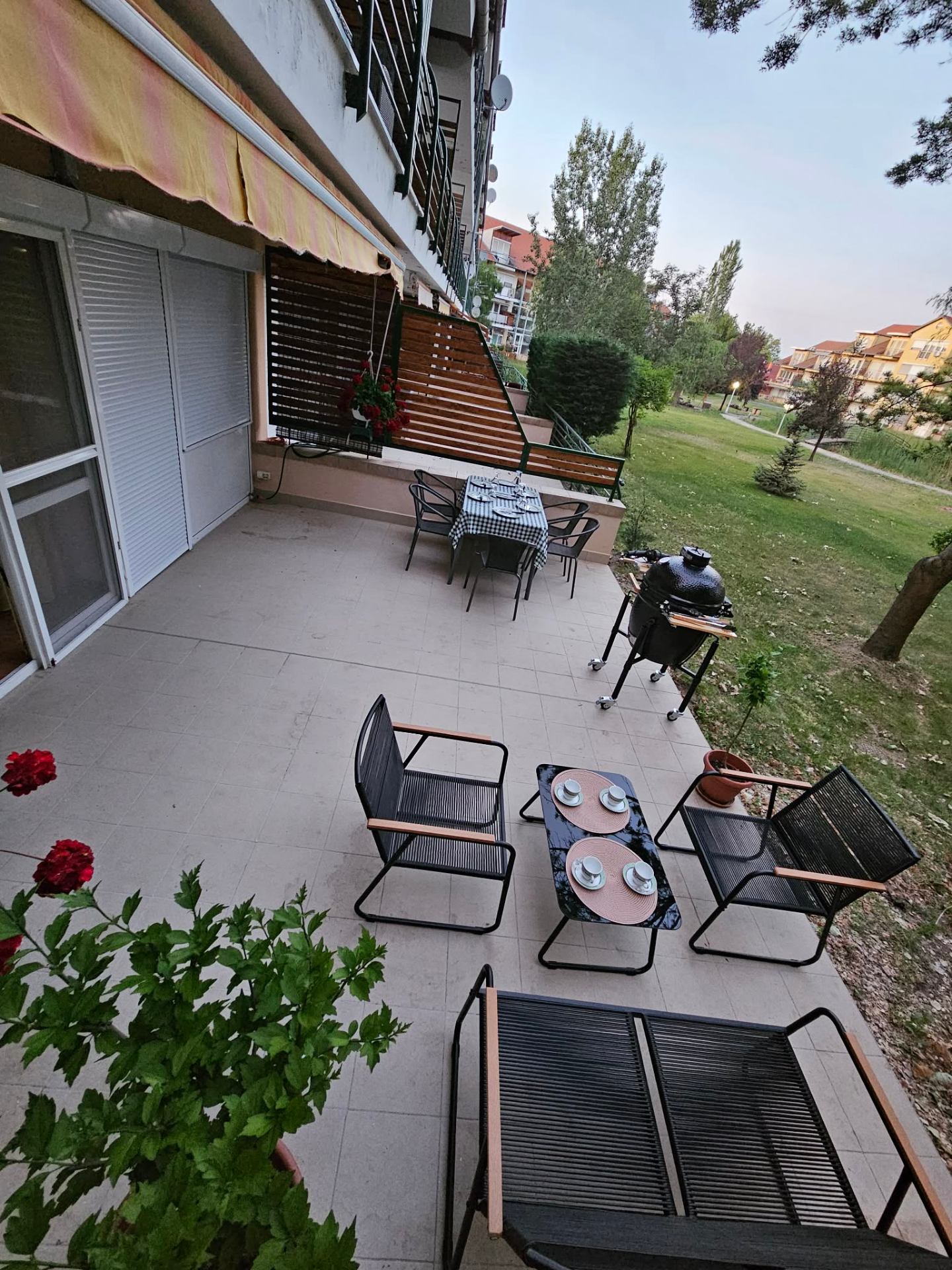 Tágas terasz kamado grillel, étkezőasztallal és zöld parkra néző kilátással